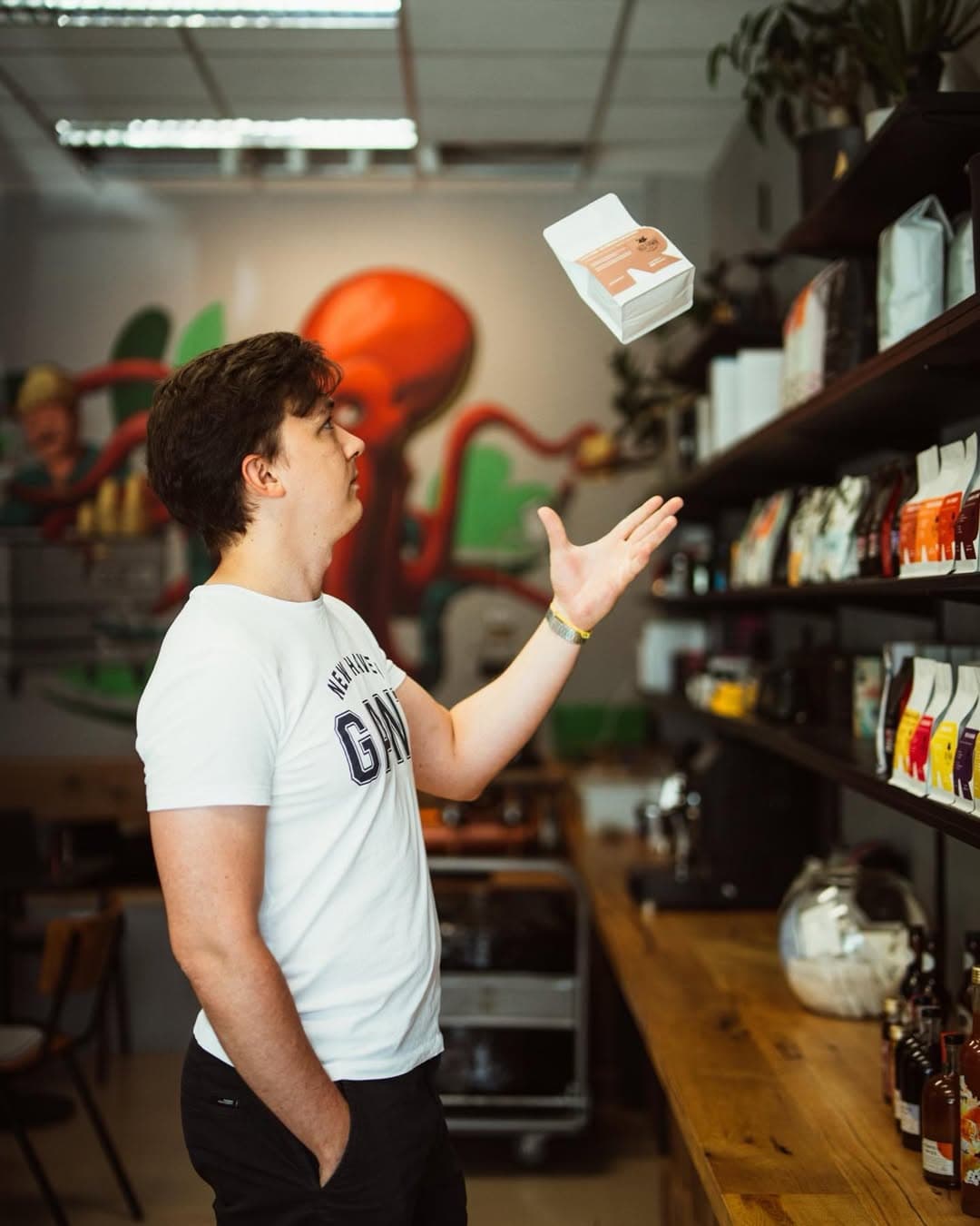 Author of the page is throwing a pack of coffe in the middle of a coffeshop.